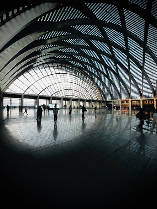 Free Spacious high-ceiling train station with arched design and people silhouettes. Stock Photo