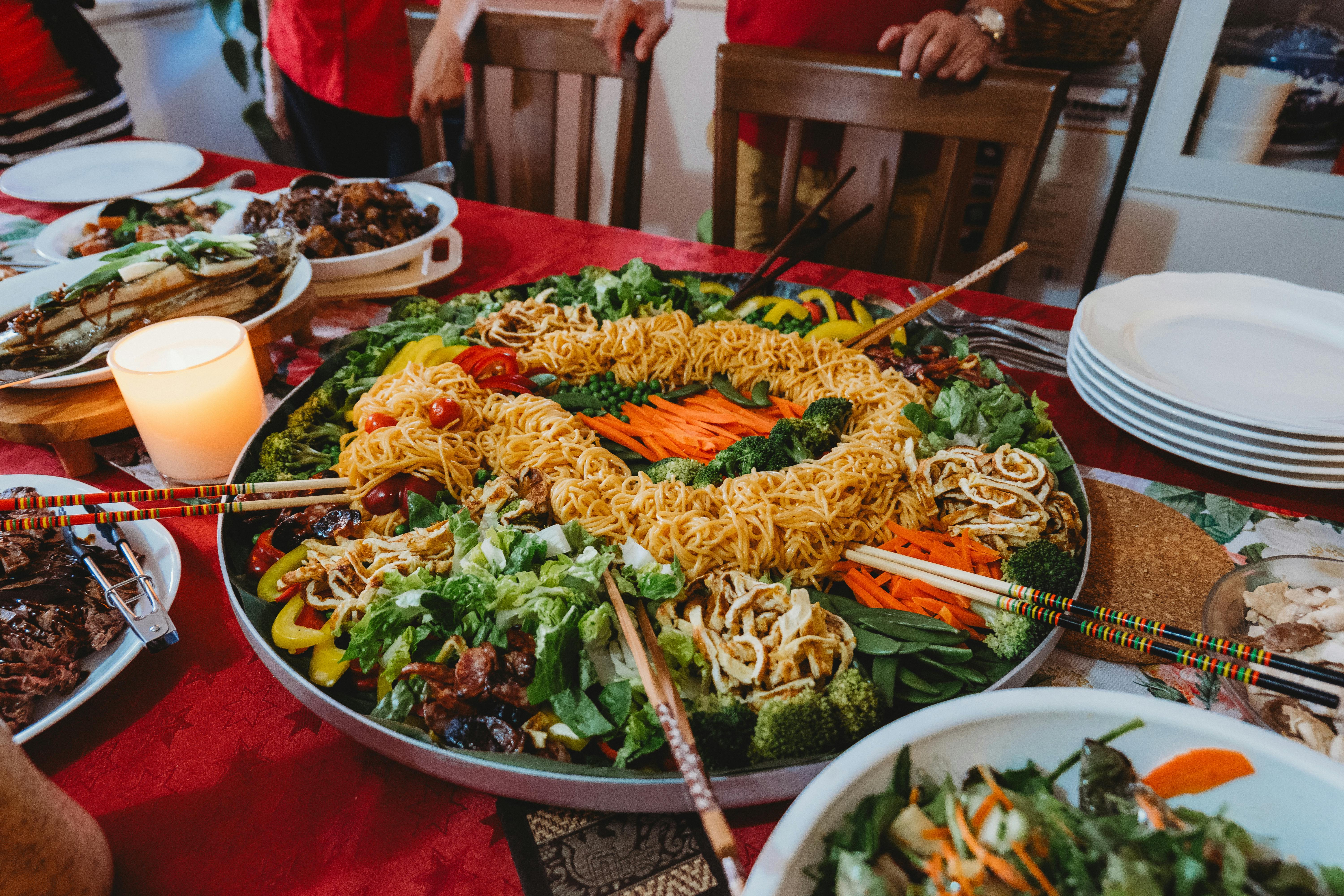 A colorful noodle platter featuring fresh vegetables and served with chopsticks on a festive table.