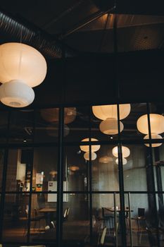 Warm interior view of a modern cafe with paper lantern lighting.