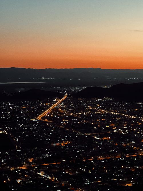 Free A breathtaking aerial view of a city in Iraq at twilight, featuring vibrant lights and a colorful sky. Stock Photo