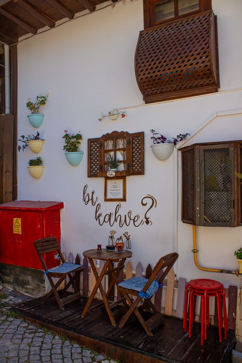 Free Cozy outdoor cafe spot with wooden chairs and decorative elements on a sunny day. Stock Photo