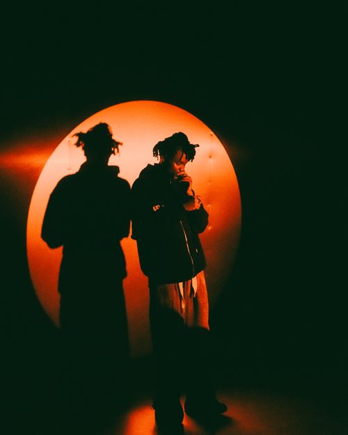 Free Person standing against a red circular light, creating a dramatic shadow effect. Stock Photo