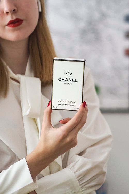 Free Woman in white blouse holding Chanel No. 5 perfume. Fashion and elegance. Stock Photo