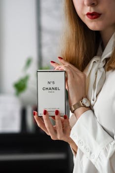 Close-up of a woman displaying a Chanel No. 5 perfume box with elegance.