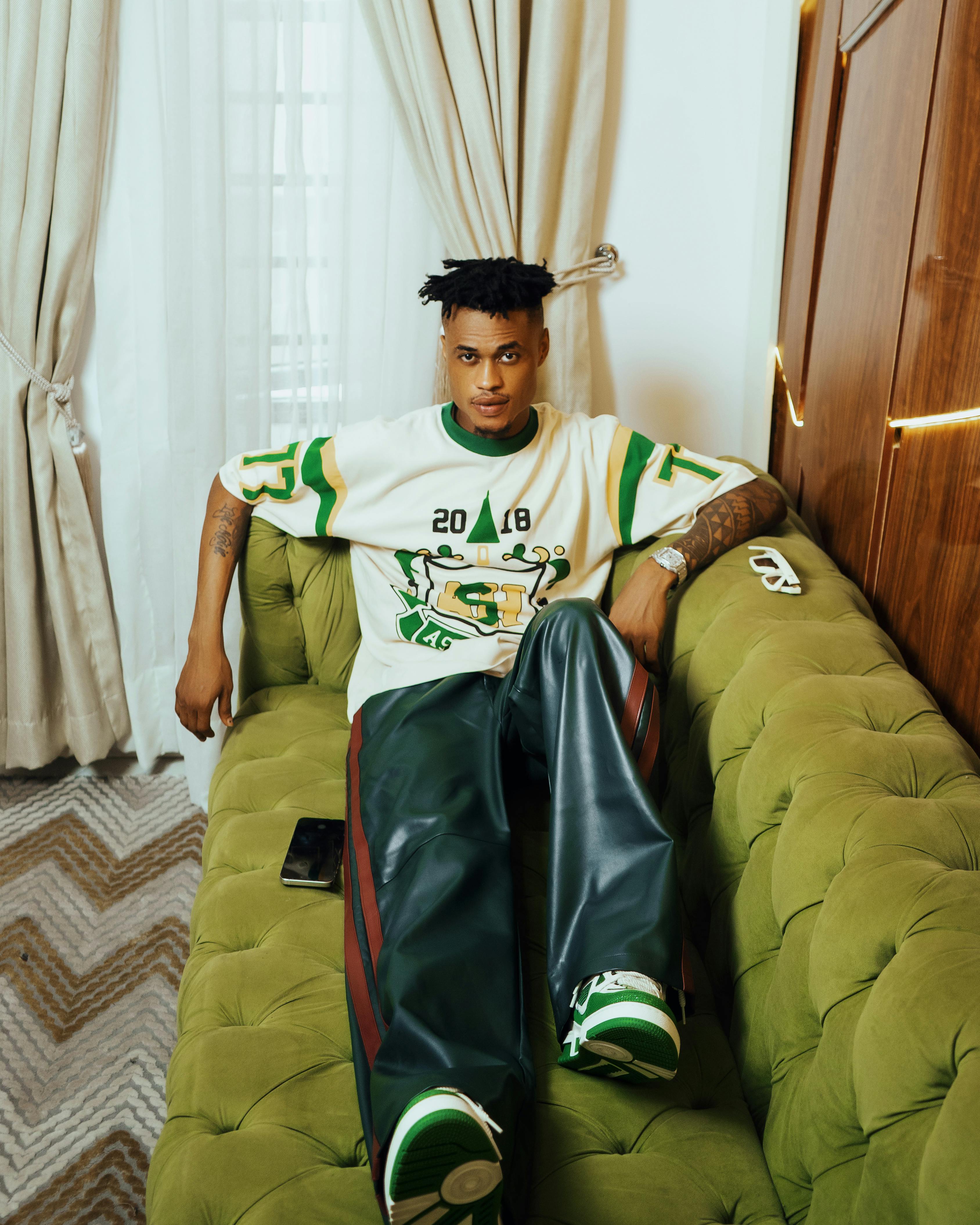 fashionable young man relaxing on green sofa indoors