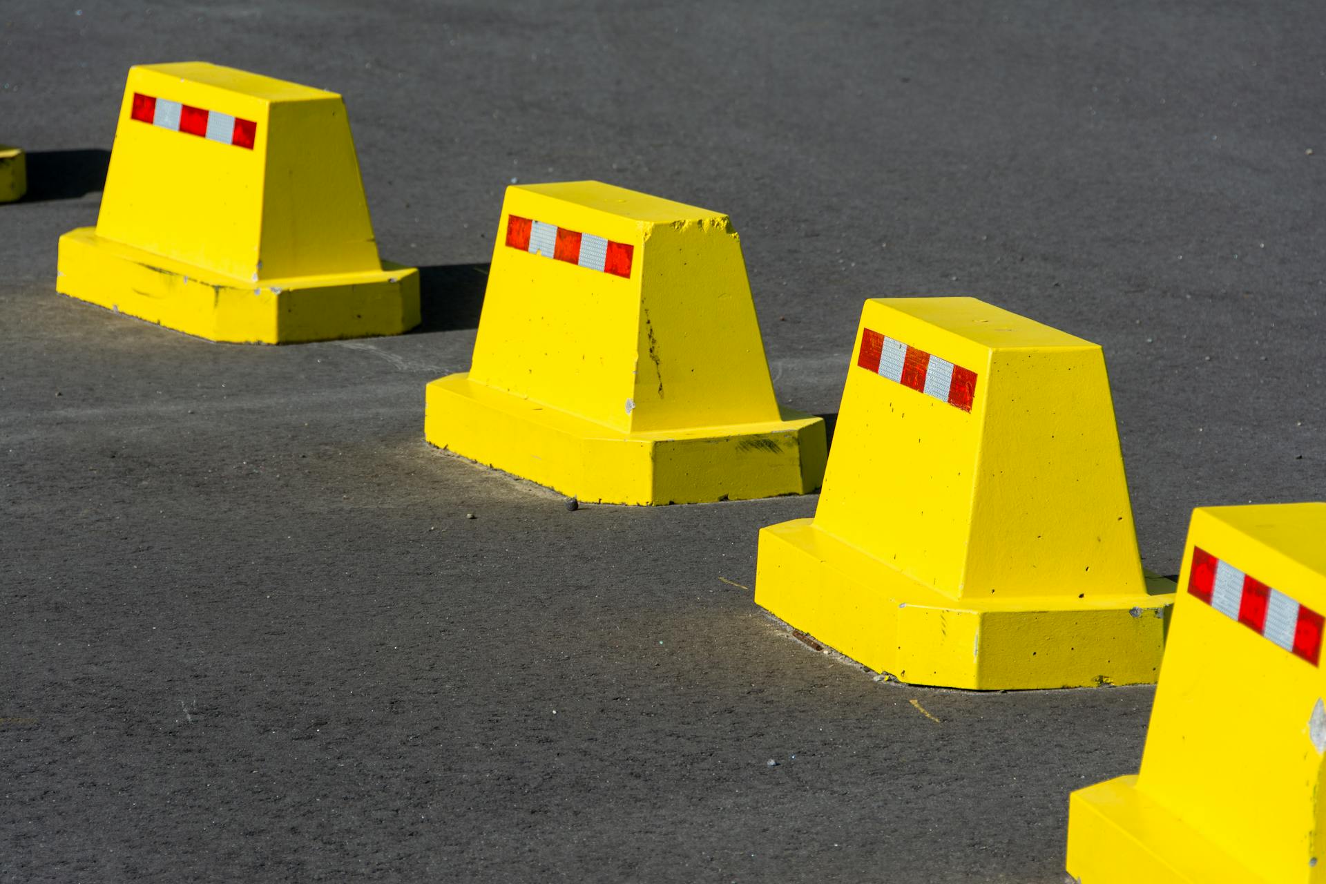 Close-up of bright yellow road markers lined on asphalt, illustrating urban safety.