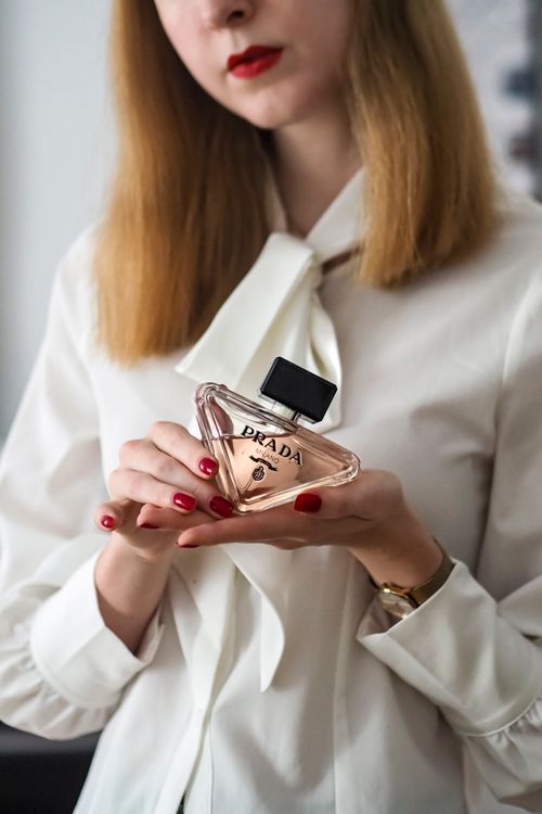 Free Close-up of a woman holding a Prada perfume bottle gracefully displayed in elegant attire. Stock Photo