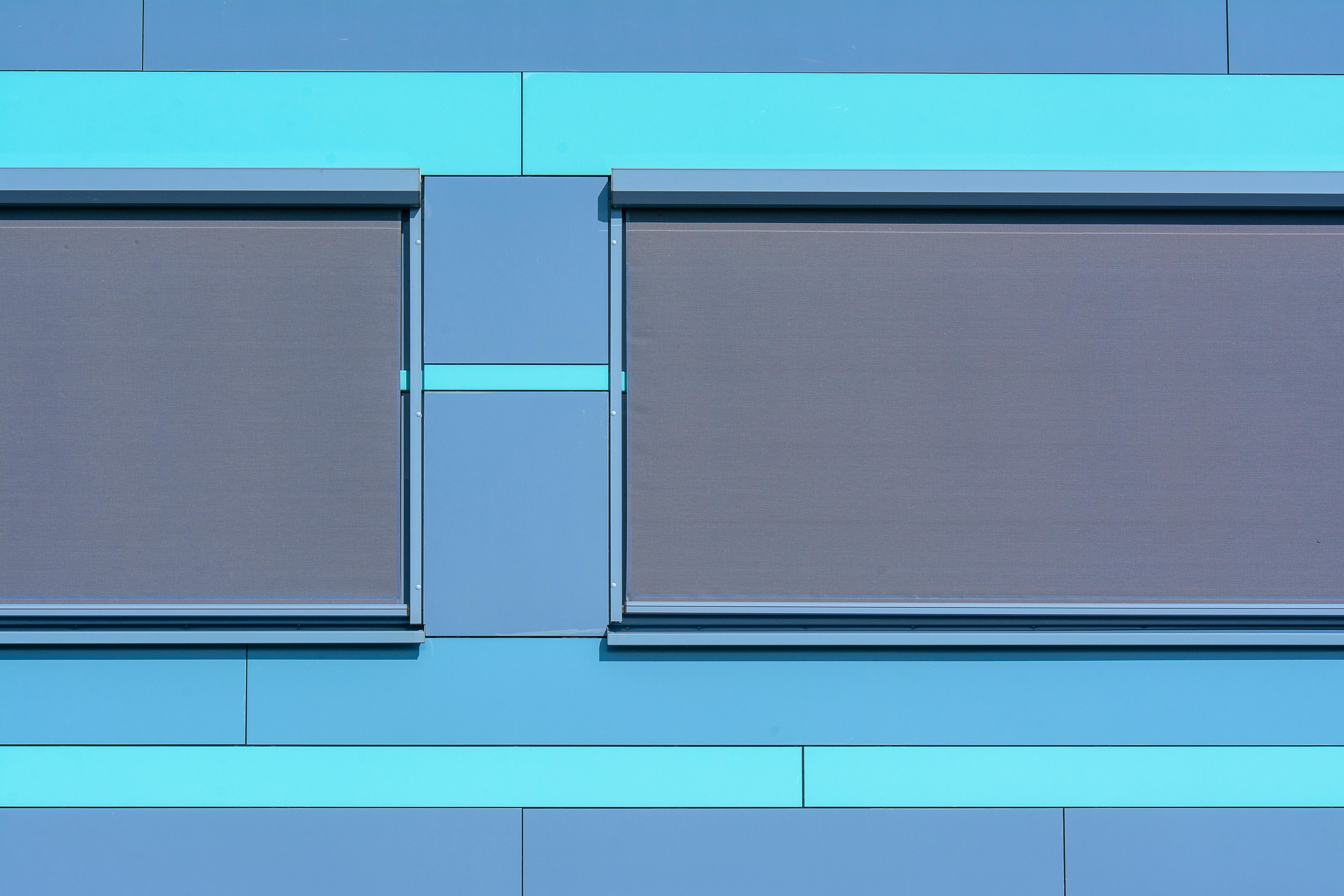 Minimalist blue facade featuring modern roller blinds for architectural appeal.