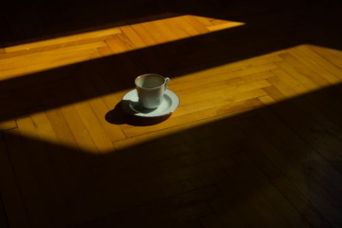 Free A single teacup casting a shadow on a sunlit wooden floor in Istanbul, Turkey. Stock Photo