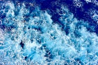 充满活力的蓝色波浪在海洋中坠毁的动态空中视角，展示了运动和能量