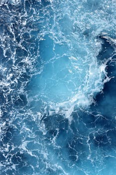 High angle shot of swirling turquoise ocean waves creating a dynamic seascape pattern.