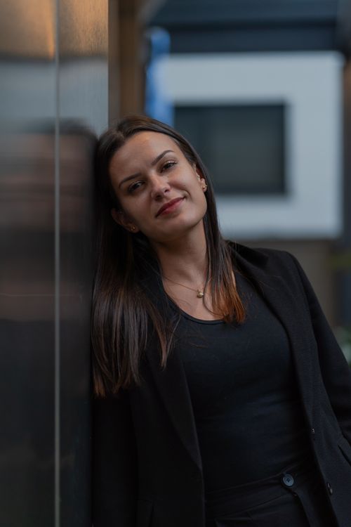 Free Portrait of a young woman leaning against a wall, expressing confidence and calmness. Stock Photo