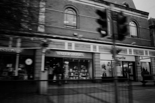 Free A dynamic black and white photograph capturing a busy Llandudno street with stores and motion blur. Stock Photo