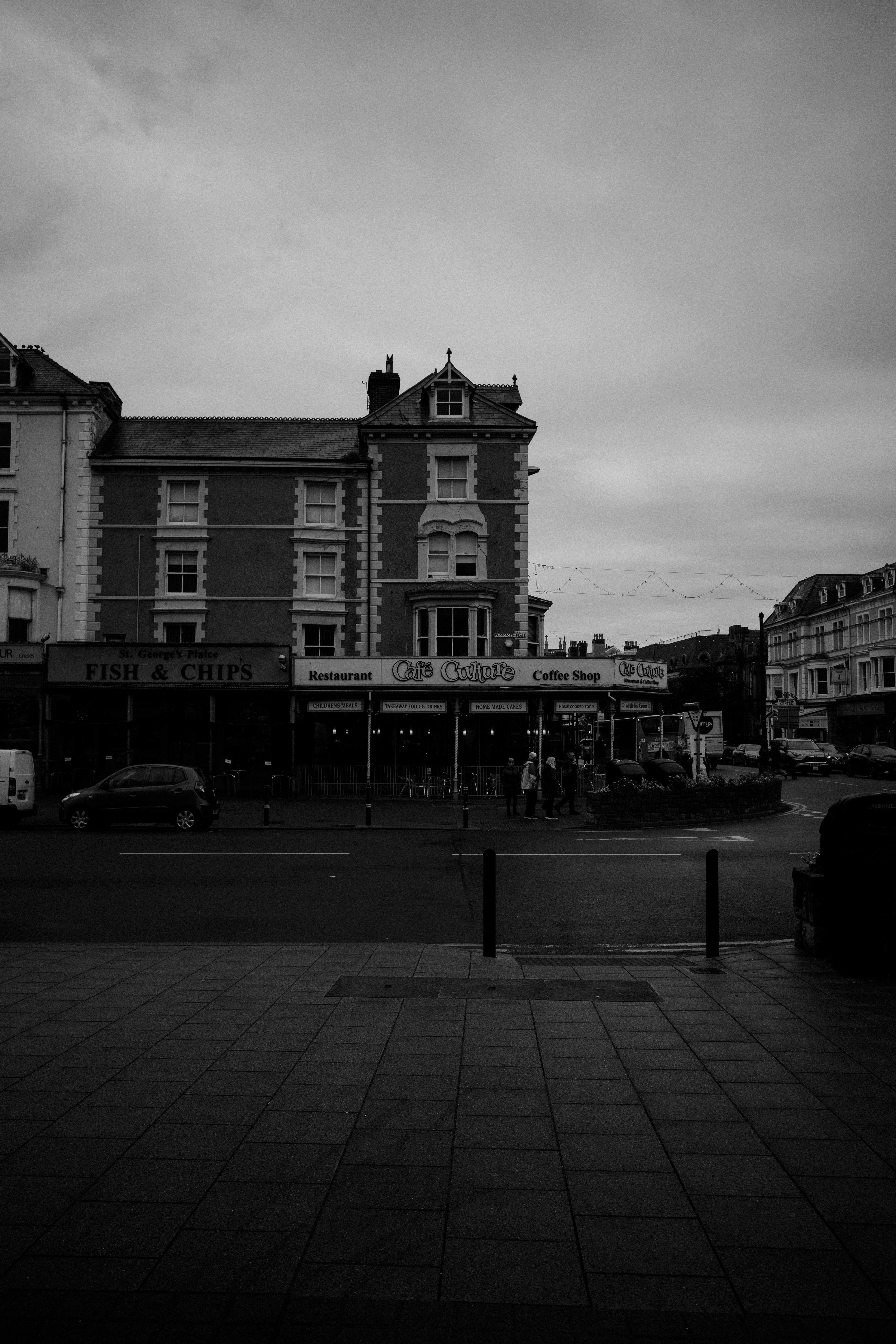 Black and white street view of Llandudno, Wales featuring historic architecture and shops.