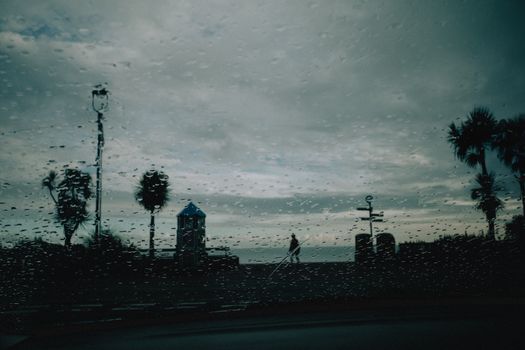 A rainy day in Llandudno, Wales, viewed through a car windshield with raindrops, creating a moody atmosphere.