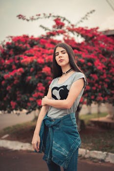 一位自信的年轻女子穿着牛仔夹克，头戴红花，在户外摆姿势