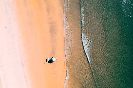Stunning aerial view of a pristine beach with two umbrellas on a sunny day.