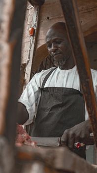 A butcher skillfully cuts meat at a traditional market in Kano, Nigeria, showcasing local culture.