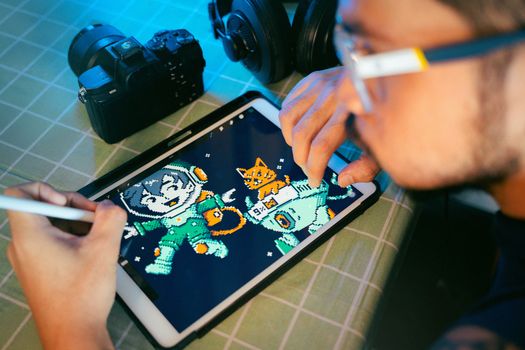 Person drawing digital art on a tablet using a stylus next to camera and headphones.