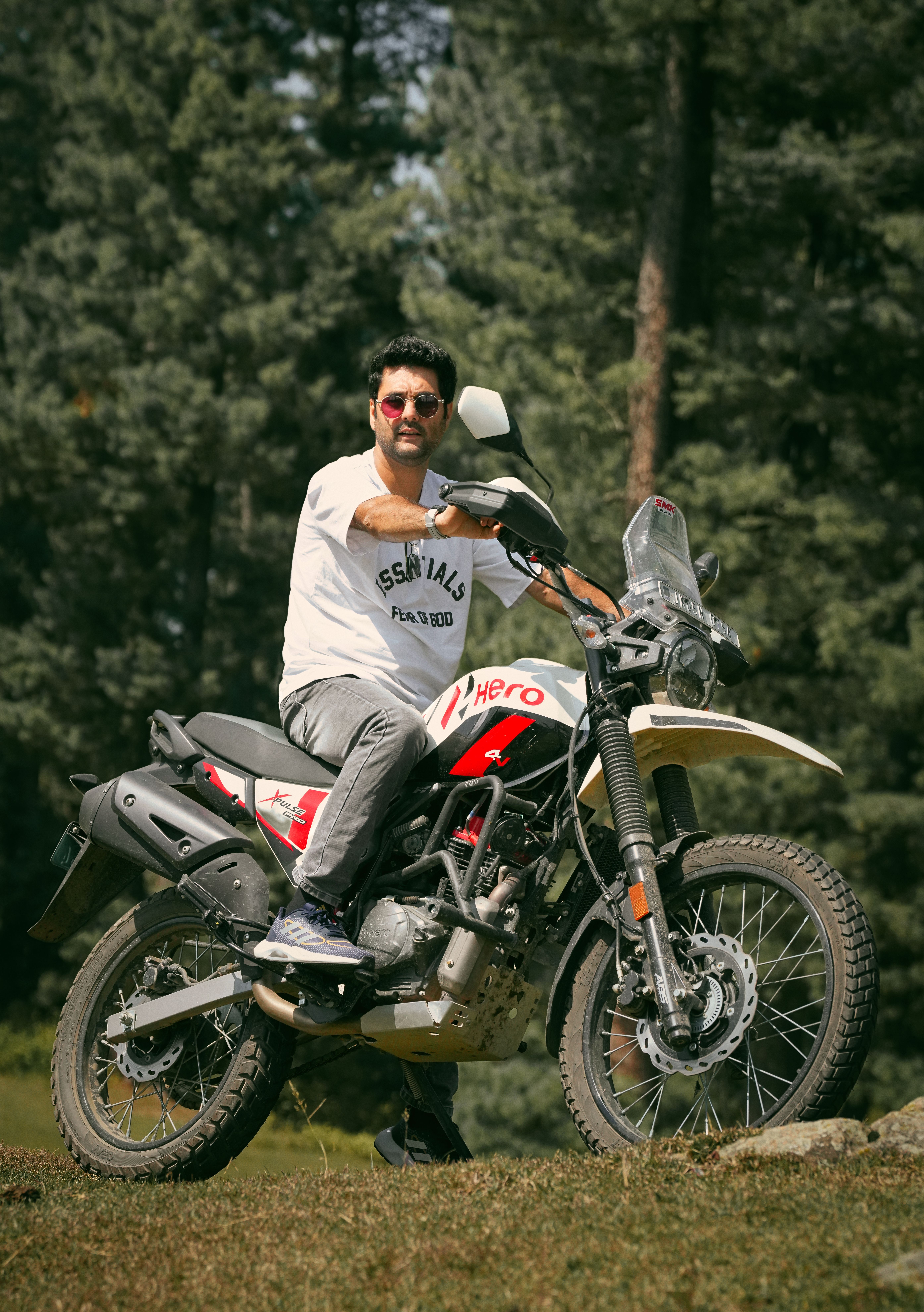 Man on a Hero motorcycle in a forest, perfect for outdoor adventure themes.