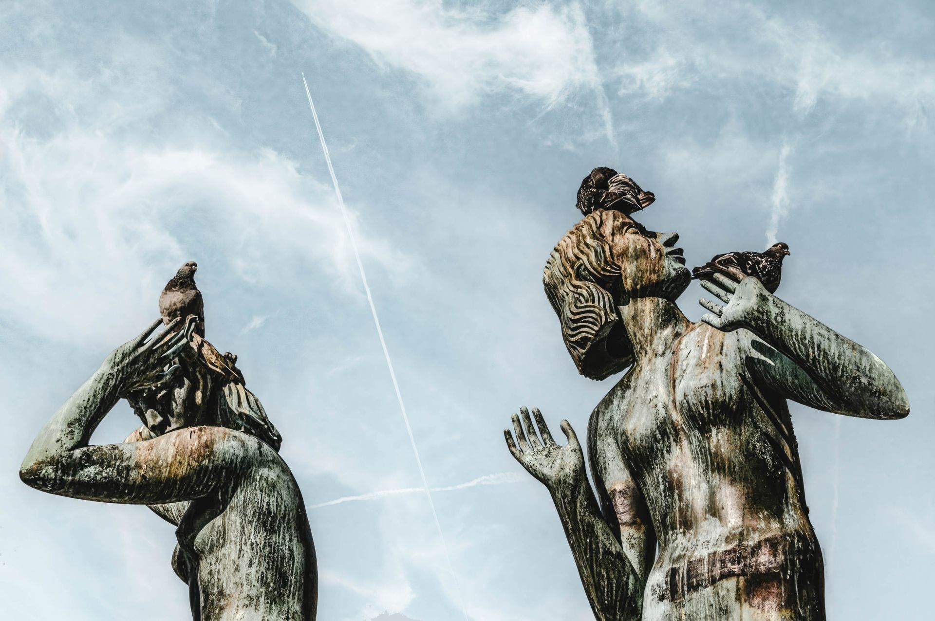 Bronze Statues with Birds Against Sky