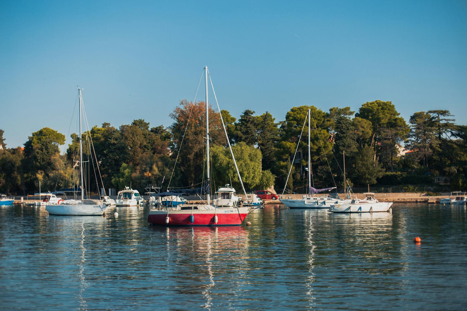 Tranquil scene with yachts docked in Zadar harbor, Croatia, under clear blue skies.
