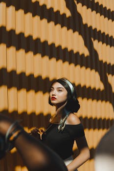 Fashionable woman posing in dramatic sunlight and shadow outdoors