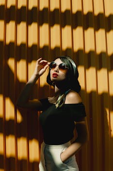 Fashionable woman with red lips and sunglasses posing elegantly in sunlight.