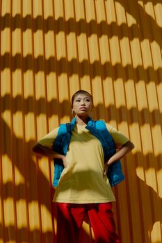 Stylish fashion portrait of a woman in colorful attire with a vibrant yellow background.