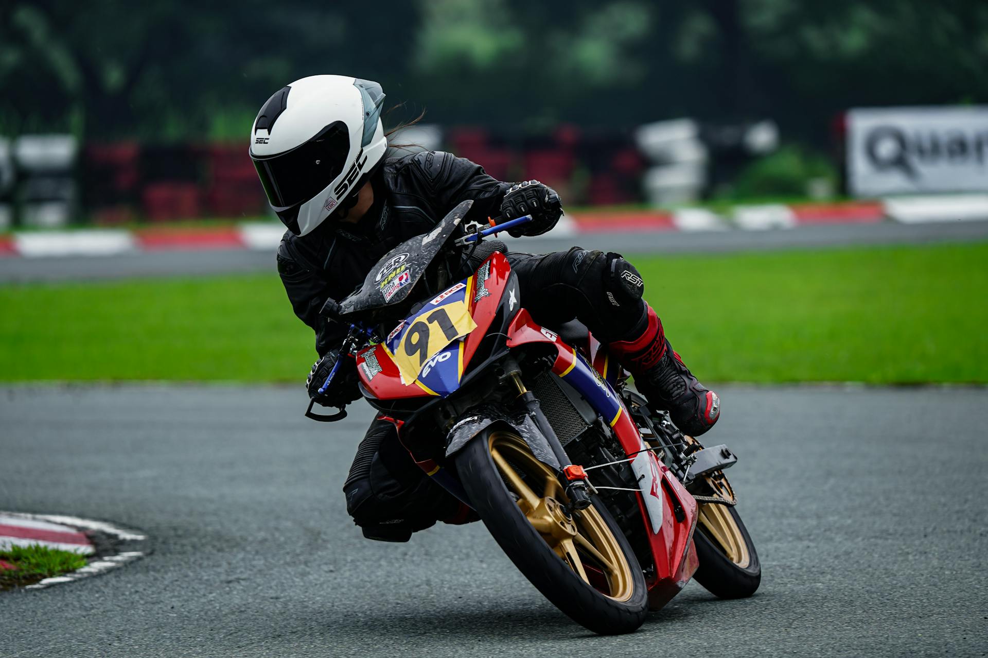 Dynamic shot of a motorcycle racer leaning into a curve on a wet race track.