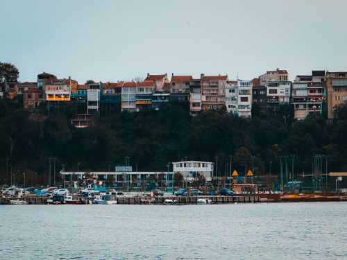 Free Colorful hillside houses overlooking a serene waterfront, providing a picturesque scenic view. Stock Photo