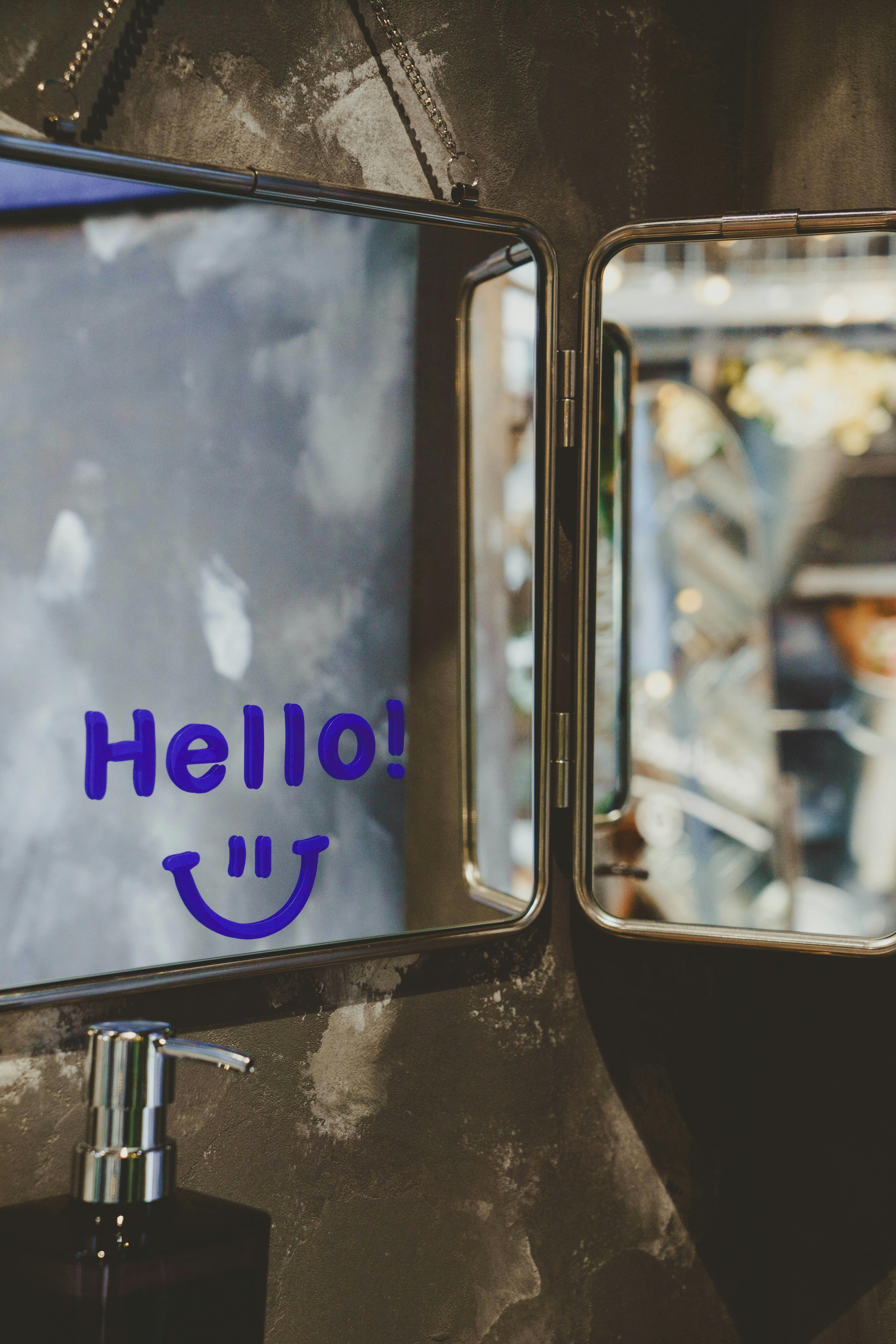 A stylish bathroom mirror with a cheerful 'Hello!' message and smiley face reflection.