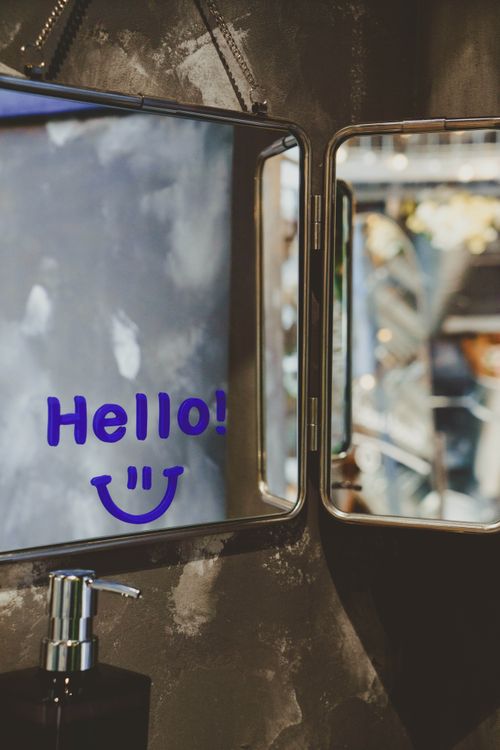Free A stylish bathroom mirror with a cheerful 'Hello!' message and smiley face reflection. Stock Photo