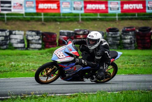 Free Motorbike racing action shot capturing a rider in full gear on a racetrack in Tarlac City, Philippines. Stock Photo