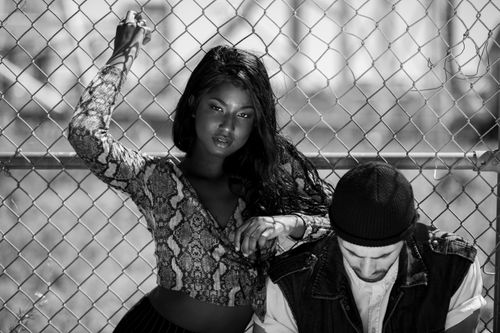 Free Stylish black and white portrait of two models posing outdoors by a fence. Stock Photo