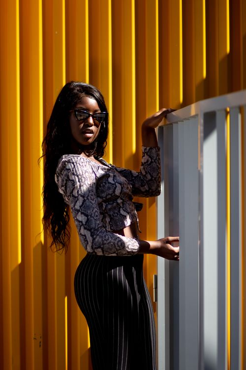 Free Fashionable woman posing confidently against a vibrant yellow backdrop. Stock Photo
