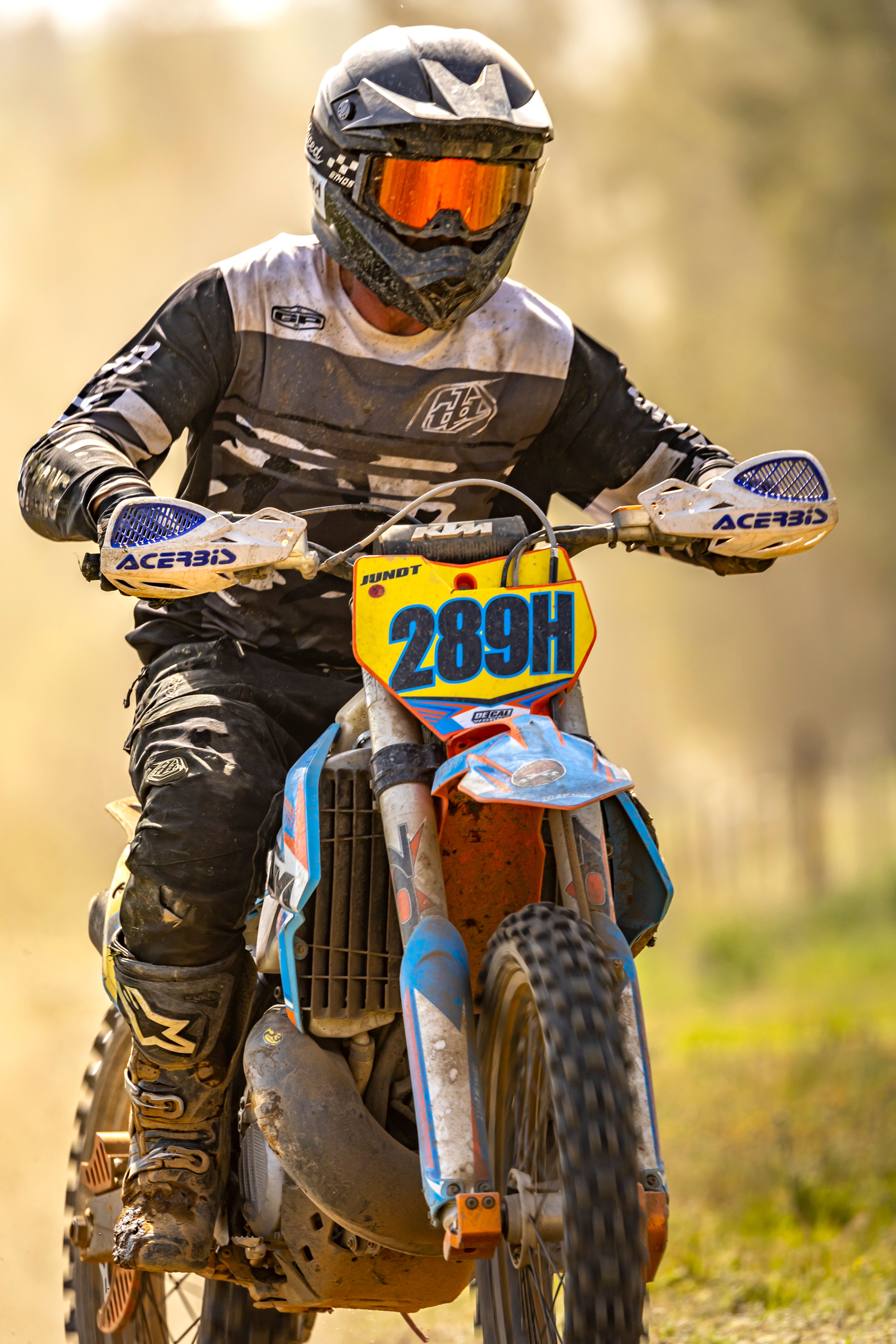 A motocross racer riding on a dusty outdoor track during the day, showcasing speed and skill.