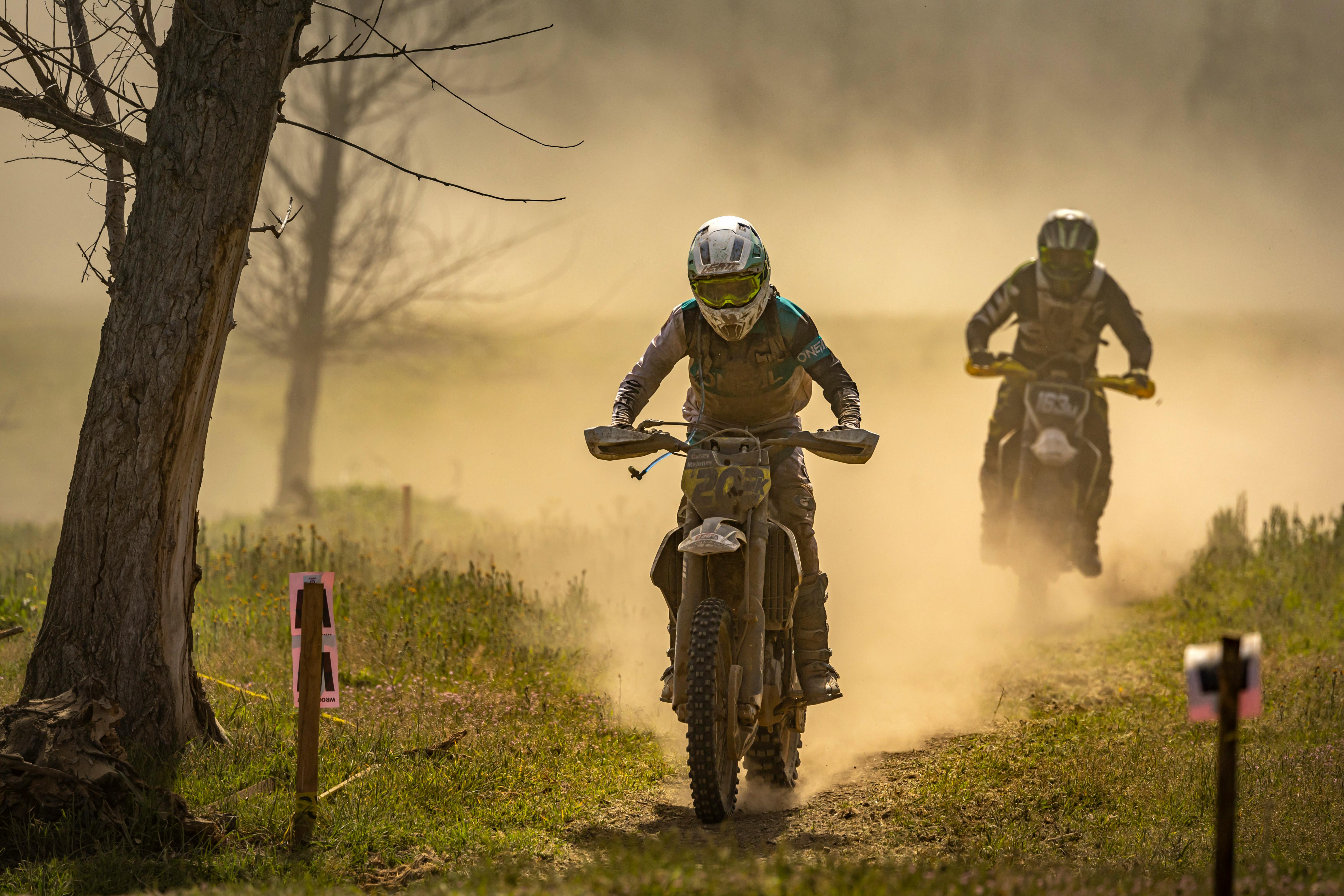 Two motorcyclists racing through a dusty forest track, highlighting adrenaline and speed.