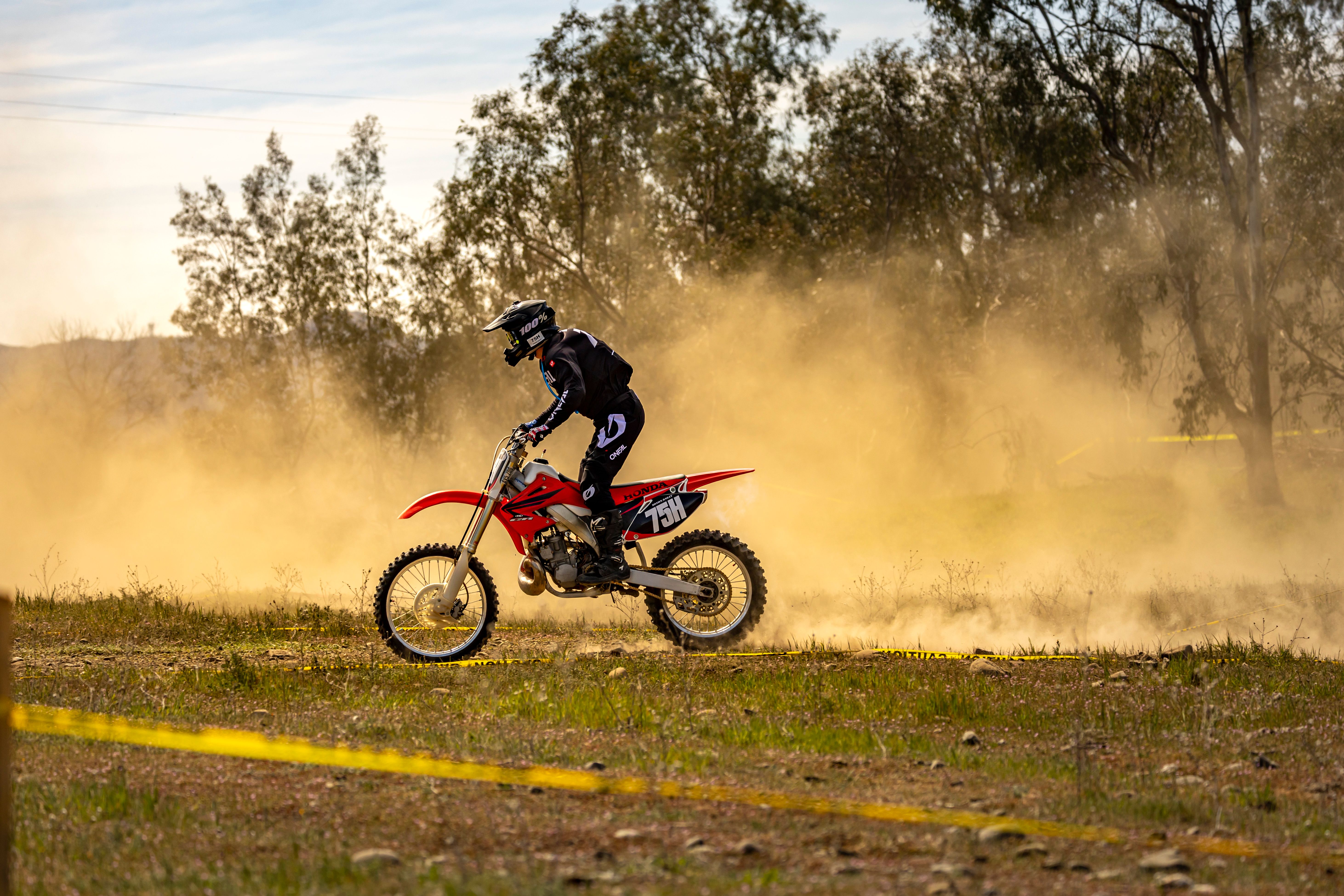 Dirt Bike Rider Kicking Up Dust in Open Field · Free Stock Photo