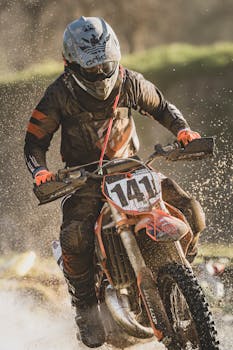 Dynamic image of a motocross rider in action splashing through mud during a race.