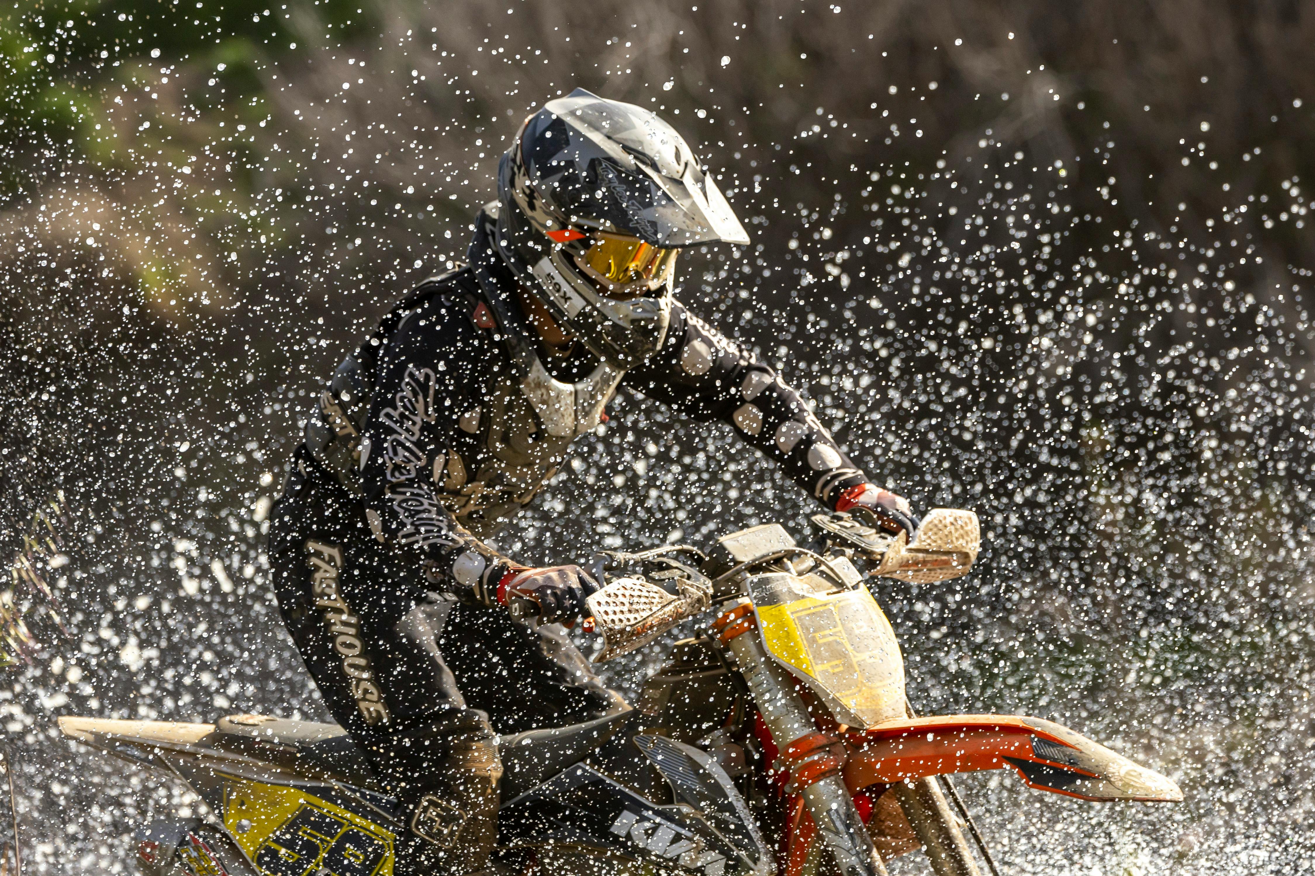 Exciting scene of a motorbike rider splashing through water during an off-road race.