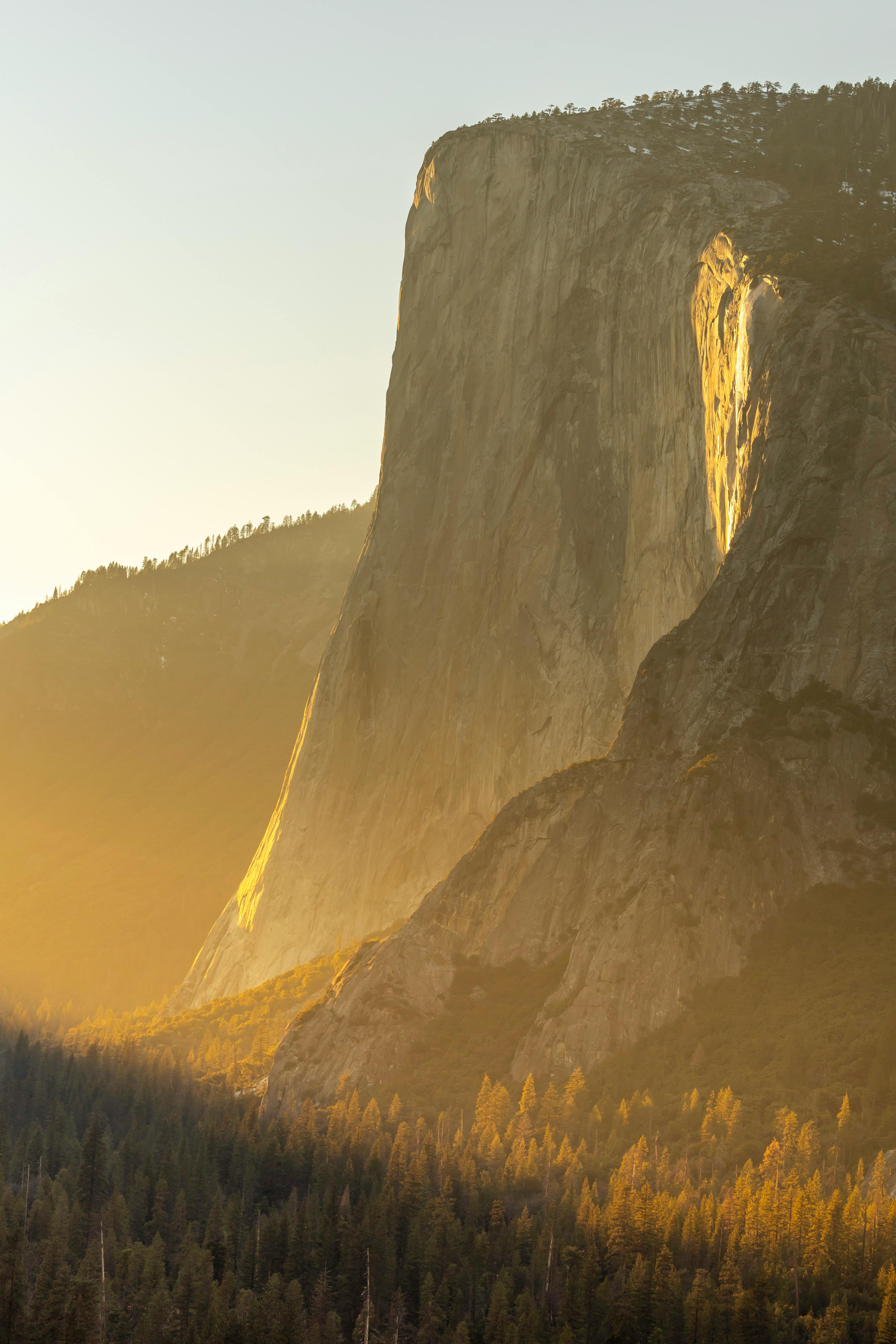 Stunning view of El Capitan at sunrise with warm light casting over the rocks in Yosemite National Park.