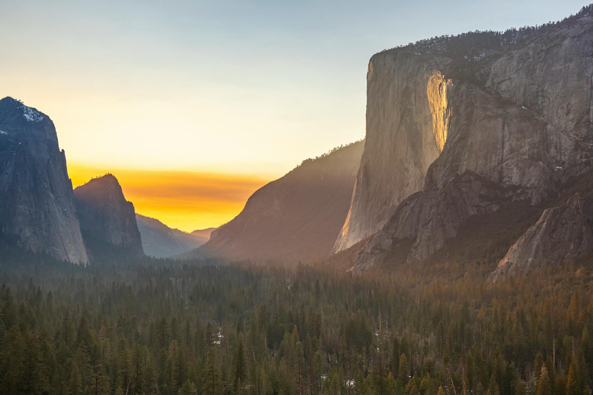 Majestic sunrise over Yosemite Valley with El Capitan and forest view, capturing natural beauty.