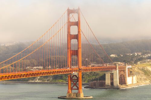 Free Iconic Golden Gate Bridge enveloped in morning fog, showcasing its vibrant structure. Stock Photo