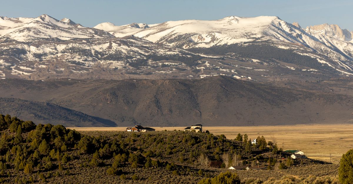 Beautiful mountain landscape with snowcapped peaks and lush green foreground under a clear blue sky.