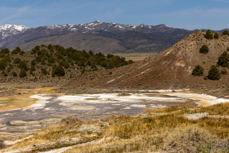 Beautiful mountain landscape with snow-capped peaks, trees, and natural terrain under a clear sky.