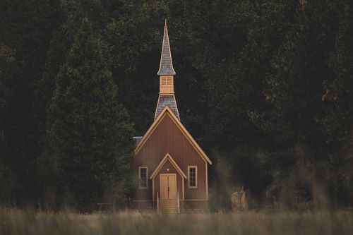 Free A serene wooden chapel nestled among lush green trees, exuding tranquility. Stock Photo