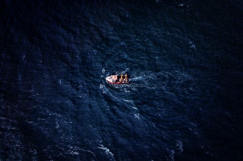 Free A top-down aerial shot of a lone fishing boat navigating the deep blue sea near Sidmouth, UK. Stock Photo