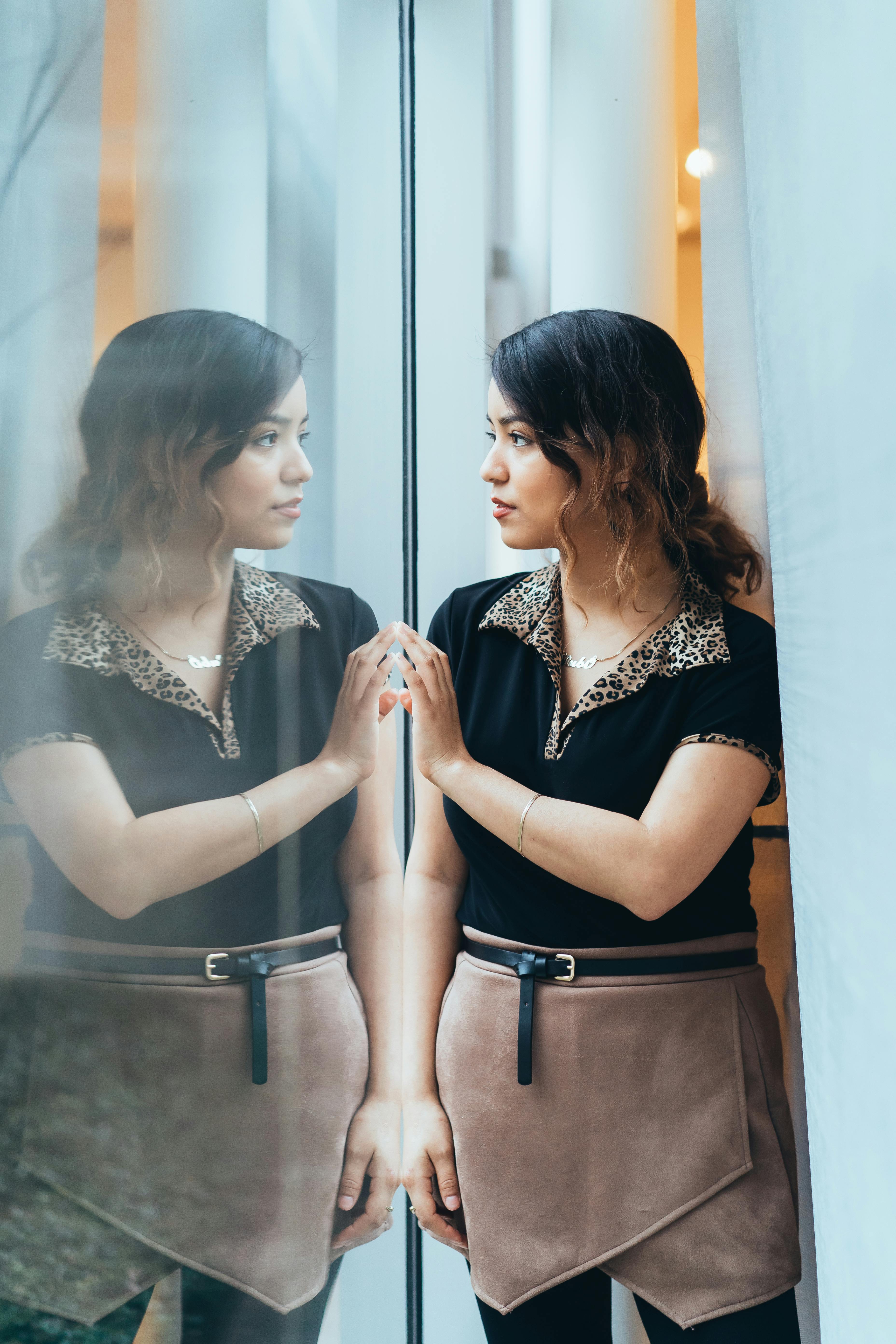 一名妇女若有所思地凝视着室内玻璃墙上的倒影