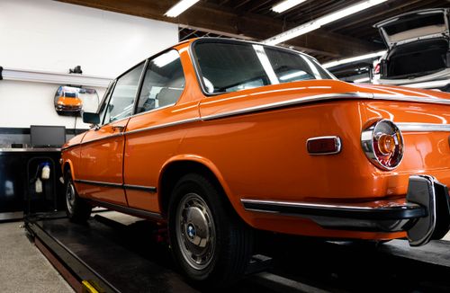 Free Classic bright orange BMW car parked in auto workshop. Perfect for automotive enthusiasts. Stock Photo